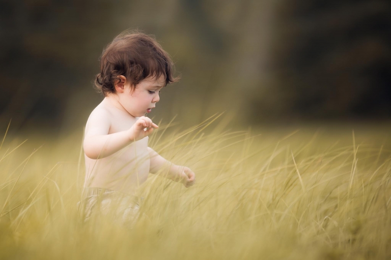 young boy walking through tall beach grass