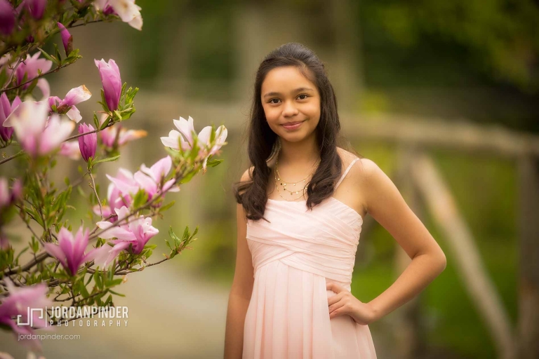 girl standing near magnolia during graduation session